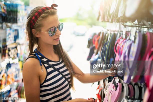 teenage girl buying flip flops at tourist shop - girl sandals stock pictures, royalty-free photos & images