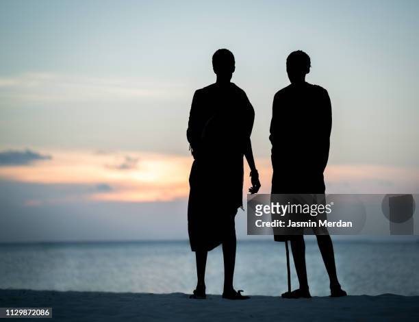 masai men silhouette on beach near sunset - east africa stockfoto's en -beelden