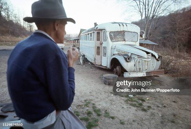 Man looking at an old bus, which was converted to a house, Pike County, Kentucky, US, 1967.