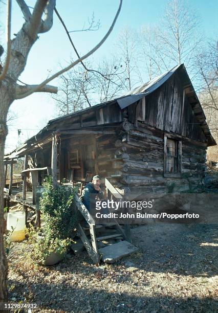 Man sitting on the stairs of the porch of his log house, Pike County, Kentucky, US, 1967.