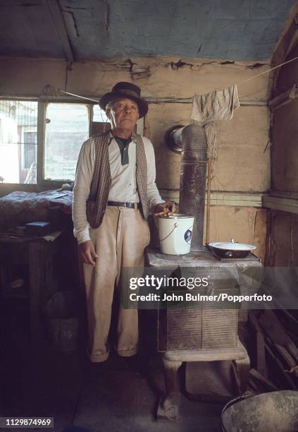 Man standing next to his 'Big Boy' coal stove, Pike County, Kentucky, US, 1967.
