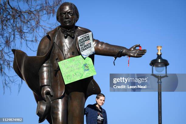 Student stands on the plinth of a statue of former Prime Minister David Lloyd George in Parliament Square during a climate protest on February 15,...