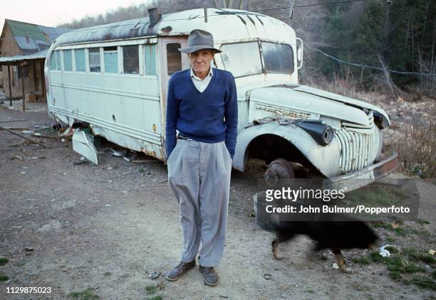 Man standing near a broken down bus, which he converted to a house, Pike County, Kentucky, US, 1967.