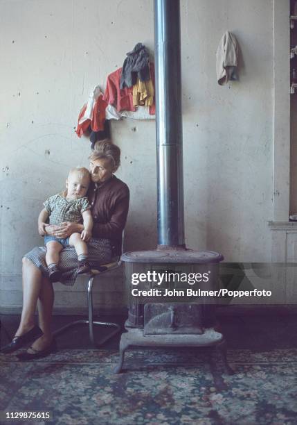 Woman and a child sitting near an old coal stove, Pike County, Kentucky, US, 1967.