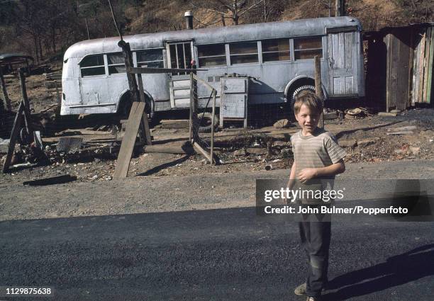 Boy in front of an old bus which was converted into a house, Pike County, Kentucky, US, 1967.