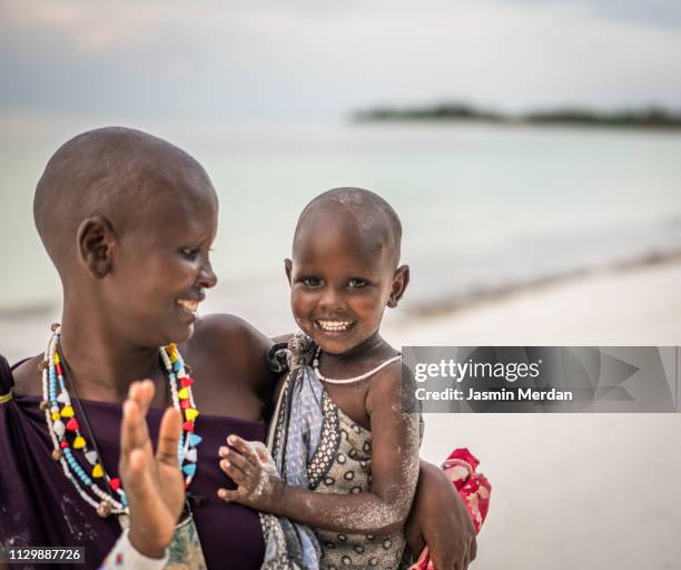 african woman with her baby girl on beach - rural africa family stock-fotos und bilder