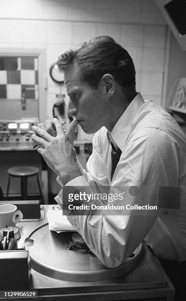 Charlton Heston giving a radio performance at a desk with a vintage microphone and a script in circa 1952.