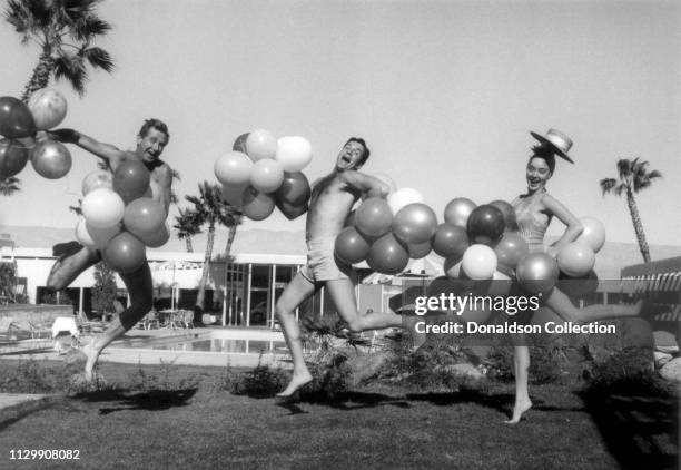 Actors Lloyd Bridges, Hugh O'Brian and Carolyn Jones pose for a portrait wearing balloons at the pool of the co-owned hotel called Whispering Waters...
