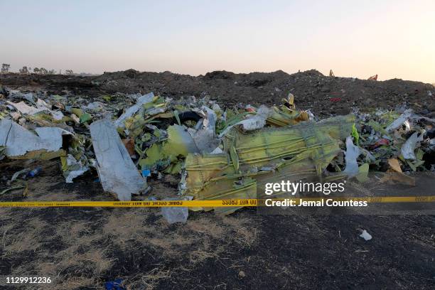 Debris lays piled up just outside the impact crater after being gathered by workers during the continuing recovery efforts at the crash site of...