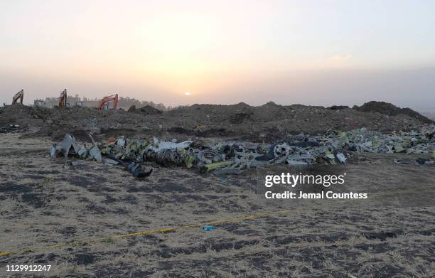 Debris lays piled up just outside the impact crater after being gathered by workers during the continuing recovery efforts at the crash site of...