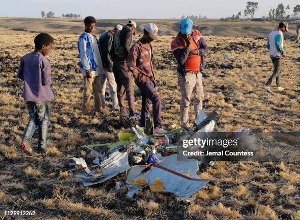 Men and boys examine a pile of debris gathered by workers during the continuing recovery efforts at the crash site of Ethiopian Airlines flight ET302...