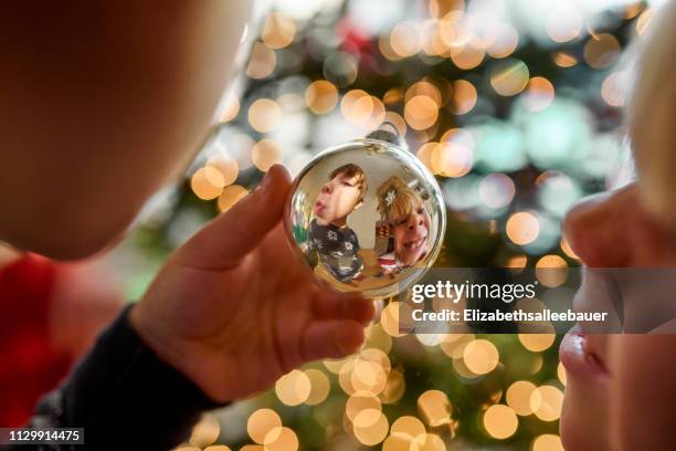 reflection of two boys making funny faces in a christmas bauble - sapin de noel humour photos et images de collection