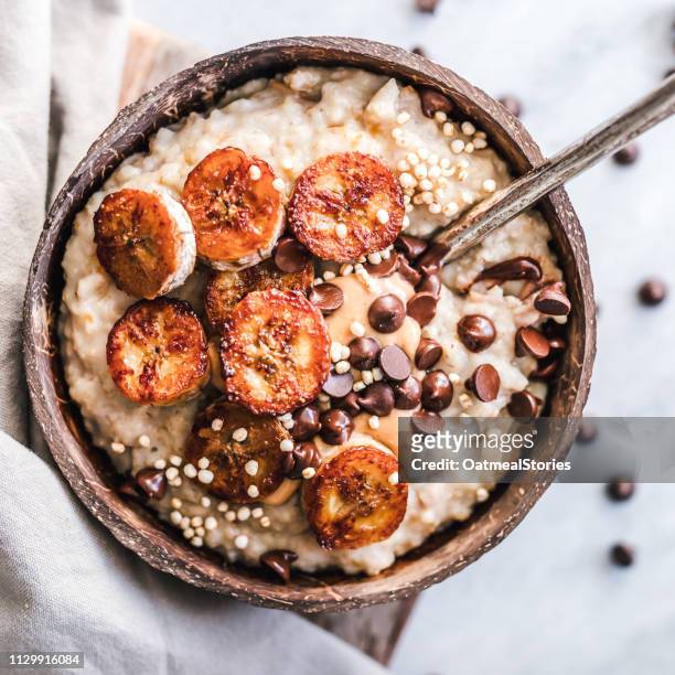 oatmeal with caramelized banana, nut butter, chocolate chips and puffed quinoa - fiocchi di avena foto e immagini stock