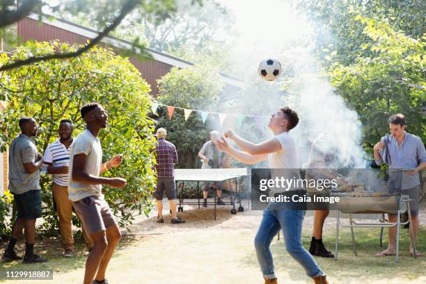 male friends playing soccer and ping pong, enjoying backyard barbecue - backyard football stock-fotos und bilder