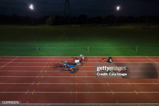 Paraplegic athletes speeding along sports track in wheelchair race at night