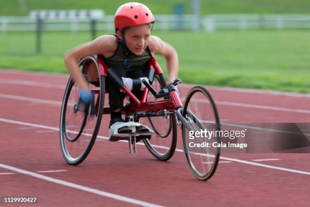 Determined, tough teenage girl paraplegic athlete speeding along sports track in wheelchair race