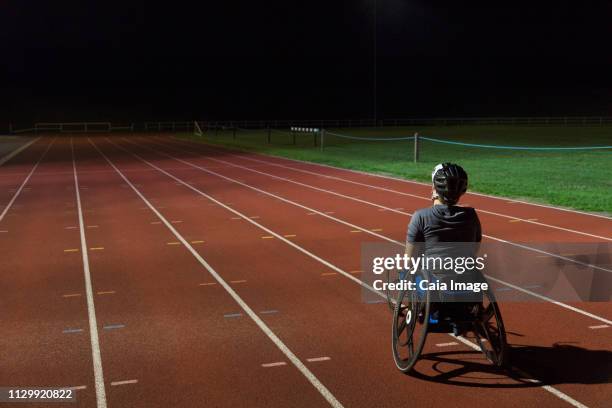 determined female paraplegic athlete training for wheelchair race on sports track at night - paraplegic race stock pictures, royalty-free photos & images