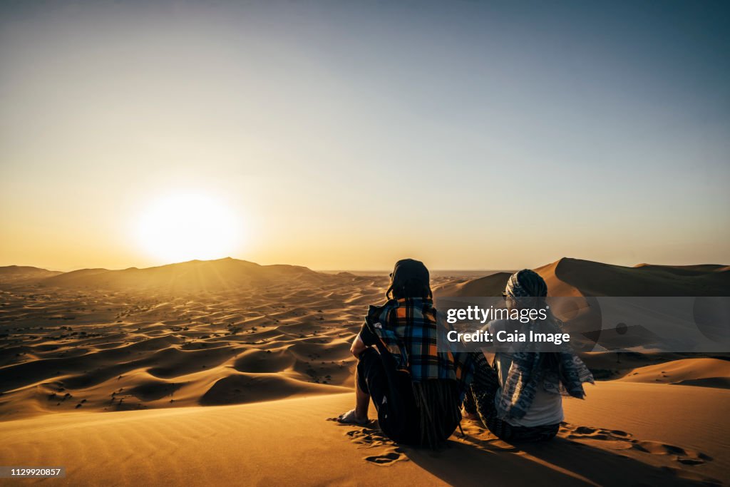 Couple enjoying sunny scenic view of remote, sandy desert, Sahara, Morocco