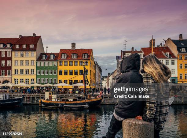 couple enjoying view of canal and colorful buildings, copenhagen, denmark - copenhagen canal stock pictures, royalty-free photos & images