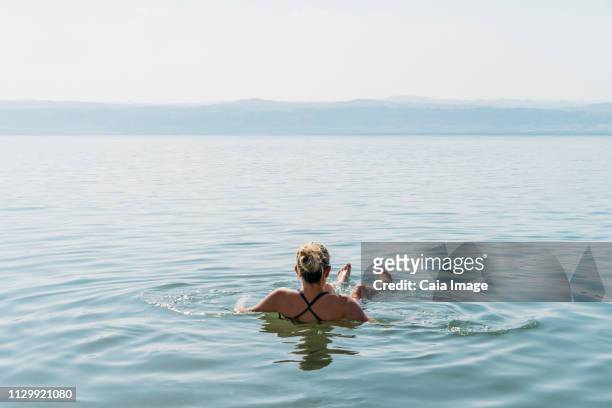 woman floating, swimming in dead sea, jordan - totes meer stock-fotos und bilder