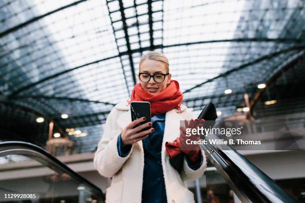 businesswoman texting on way to the office - goed gekleed stockfoto's en -beelden