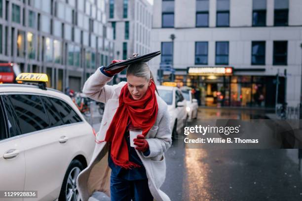 businesswoman running in rain on busy street - busy woman stockfoto's en -beelden