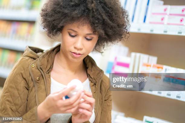 young woman buying at pharmacy - medicine bottle stock pictures, royalty-free photos & images