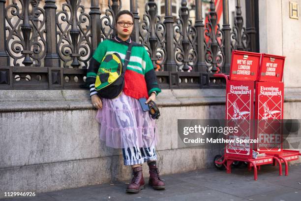 Guest is seen on the street wearing green/white stripe sweater, pink sheer skirt, black/white pants, brown boots and soccer ball design bag during...