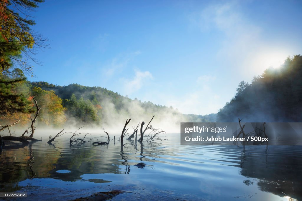 Early In The Morning When The Sun Is Rising And Fog Patches Are Moving Over The Water
