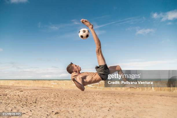 player kicking the ball in the air - beach football stock pictures, royalty-free photos & images