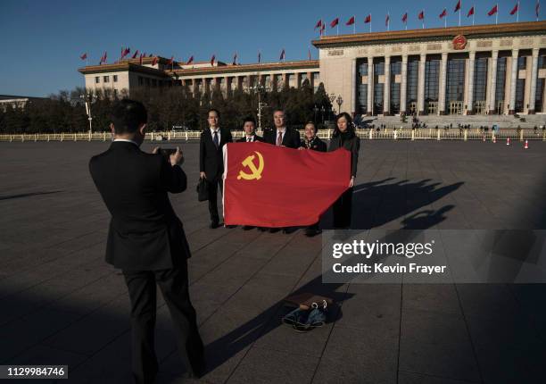 Delegates pose with the Communist Party flag as they arrive for the third plenary session of the National People's Congress at The Great Hall Of The...
