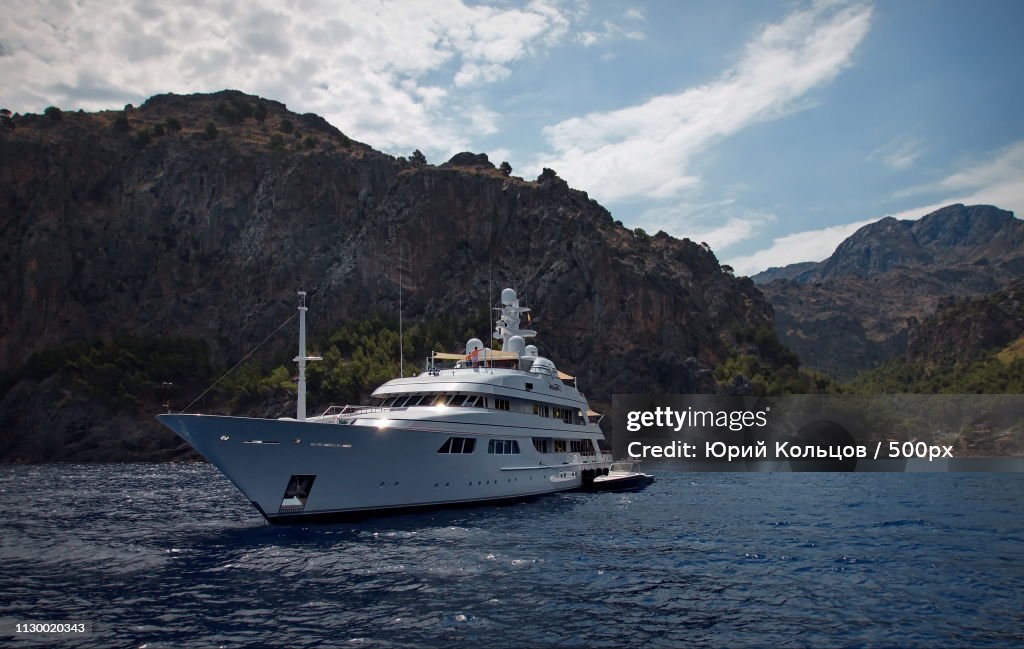 Yacht sailing in sea and mountains in background