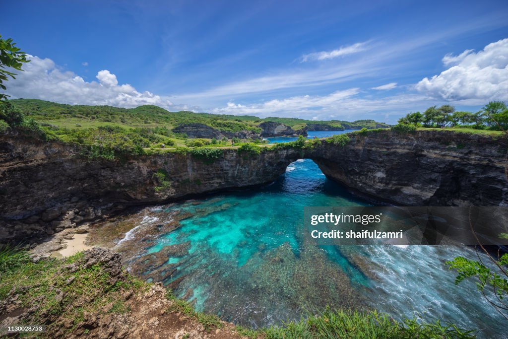 Beautiful arched broken beach with big waves and crystal clear water in Nusa Penida in Bali, Indonesia.