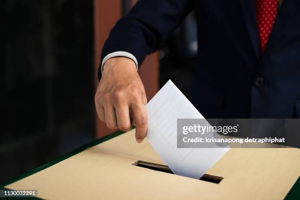 election concept. hand dropping a ballot card into the vote box,drop the ballot - referendum stockfoto's en -beelden