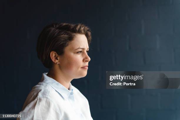 thoughtful female doctor against wall - doctor side view stock pictures, royalty-free photos & images