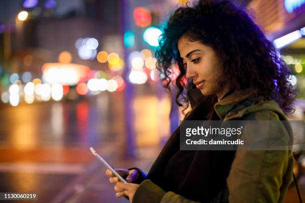 young woman walking on the street at night - arab and mobile stock pictures, royalty-free photos & images