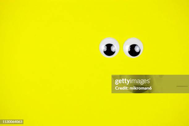 googly eyes looking up on colored background - comic augen stock-fotos und bilder