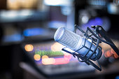 Microphone in a professional recording or radio studio, equipment in the blurry background