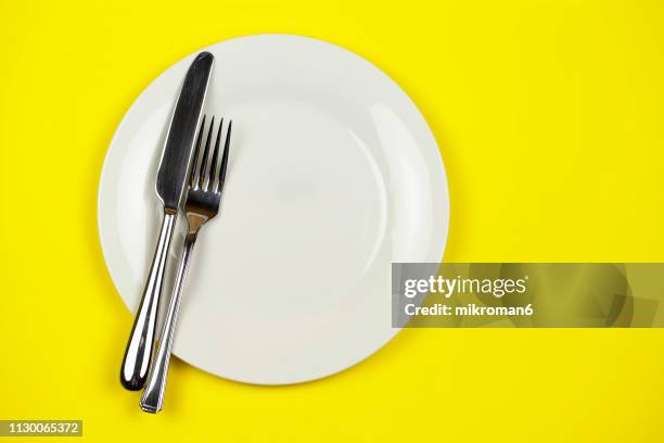 directly above shot of plate with fork and table knife - utensile per mangiare foto e immagini stock