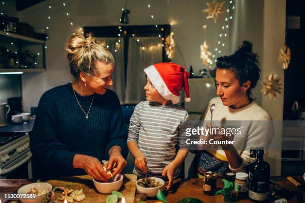 two women preparing christmas dinner with young boy - warmes abendessen stock-fotos und bilder