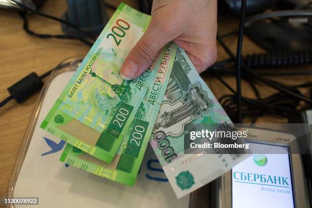 An employee displays ruble banknotes at the retail store of a gas station, operated by Tatneft PJSC, in Kazan, Tatarstan, Russia, on Thursday, March...