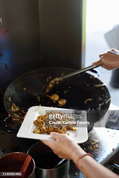 hand scooping char kway teow onto a plate - char kway teow stock pictures, royalty-free photos & images