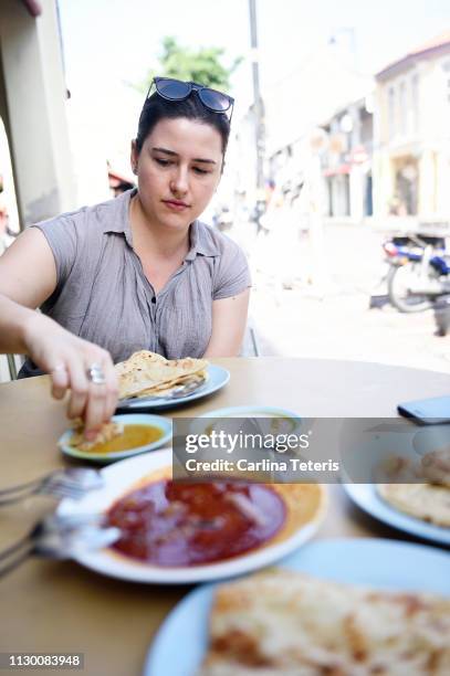 caucasian woman eating roti canai - roti canai stock pictures, royalty-free photos & images