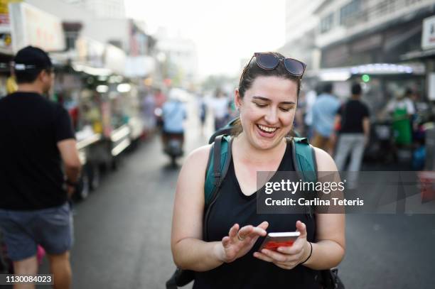 woman traveler reading from her phone at a penang street market - travel market asia stock pictures, royalty-free photos & images