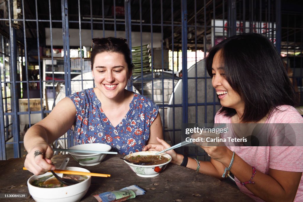 Two women tasting traditional Malaysian food