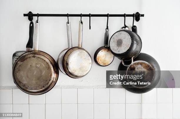 pots and pans hanging on a kitchen wall - pot foto e immagini stock
