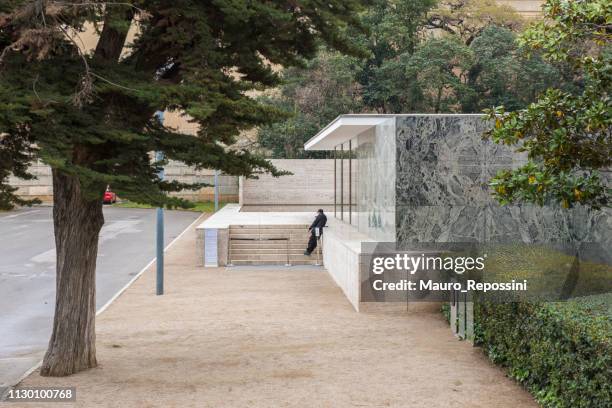 um homem parado na frente de "o pavilhão de barcelona", no distrito de montjuic, em barcelona, espanha. - casa de jardim ou parque - fotografias e filmes do acervo