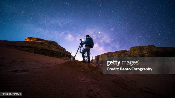 an unidentified photographer in wadirum desert under the milky way, jordan - photographer fotografías e imágenes de stock