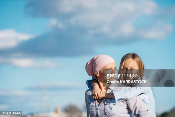 a woman with cancer is next to her daughter. a girl is hugging a woman happy - cancerland 2019 bildbanksfoton och bilder