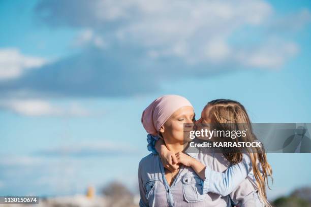 a woman with cancer is next to her daughter. a girl is hugging a woman happy - best bosom stock-fotos und bilder